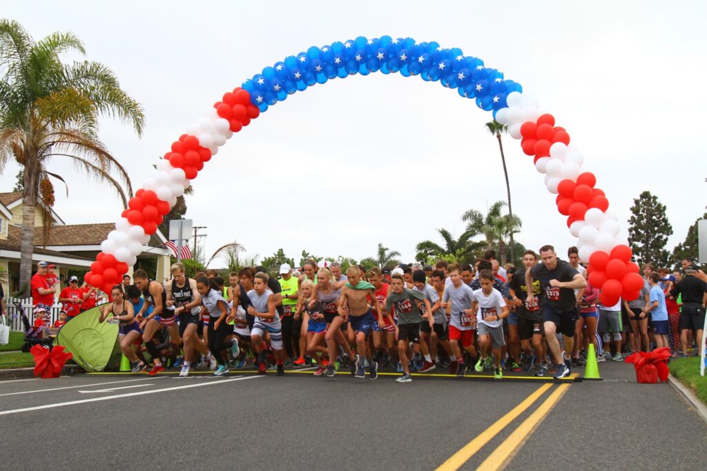 Runners at the starting line with red white and blue balloon arch
