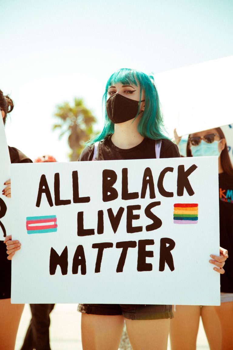 Blue haired girl, wearing a mask holding All Black Lives Matter sign